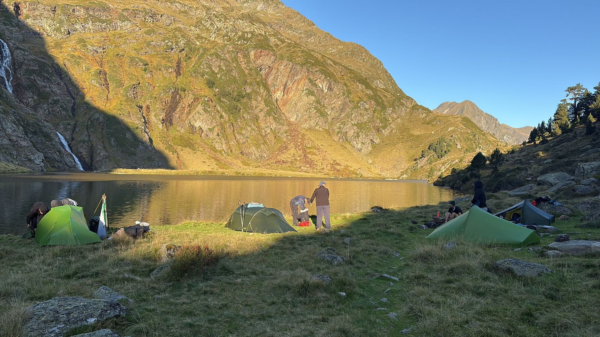Kampplaats aan een stil bergmeer, in het gouden ochtendlicht.
