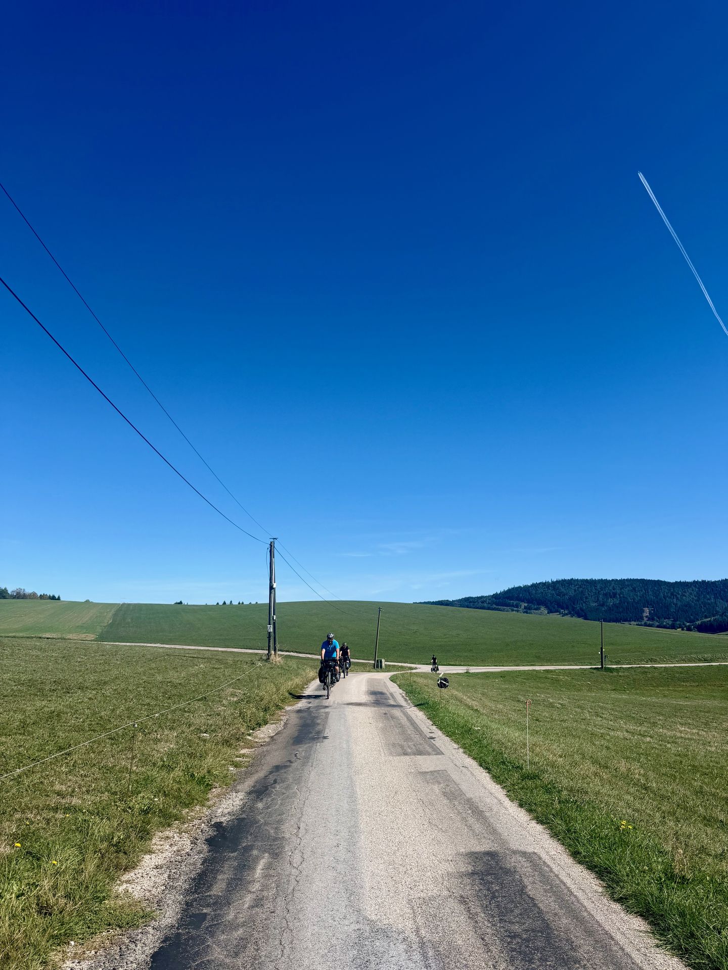Bikepacker op een smal weggetje tussen de weiden van de Jura