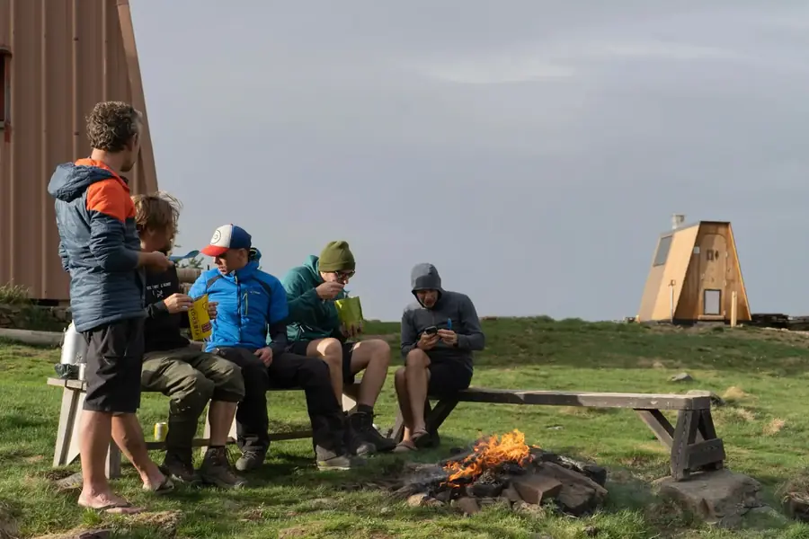 Wandelaars eten bij een kampvuur naast een berghut in de Val d'Aran