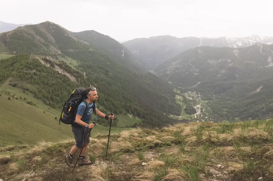 Wandelaar met trekkingrugzak boven een stille vallei in de Maritieme Alpen