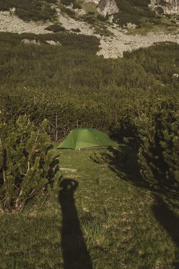 Groene tent op een open plek tussen de bergdennen